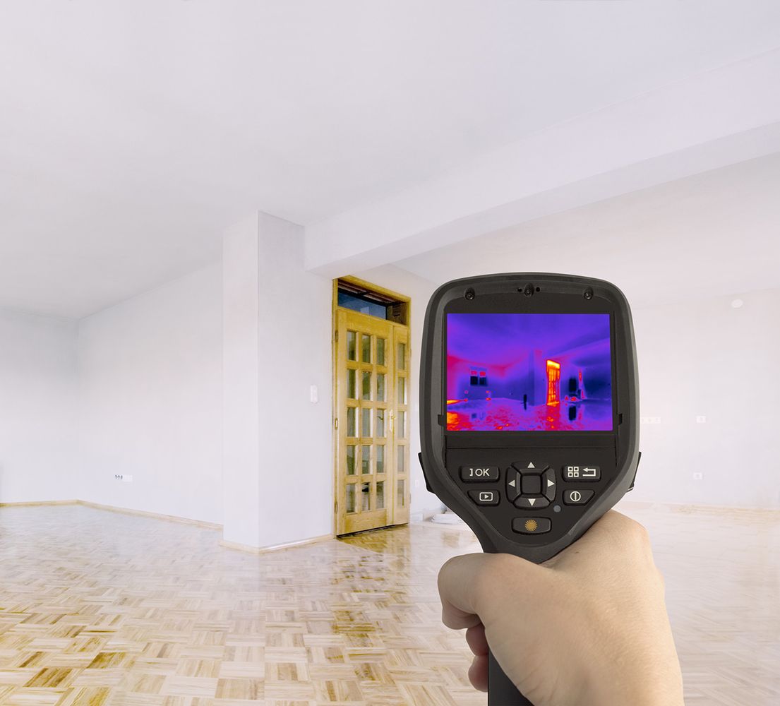 Ein Wärmemessgerät wird in ein Wohnzimmer gehalten